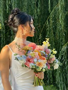 a woman holding a bouquet of flowers in her hand and looking off into the distance