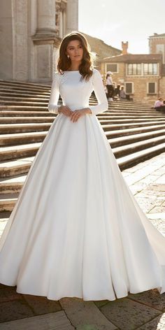 a woman in a white wedding dress standing on steps with her hands on her hips