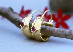 Wide ornamented solid yellow, white or rose gold hoop earrings with rubies in 14k, 18, or 22k gold. These Gold Hoop earrings are a special take on ornamental jewelry.These wide oriental-style hoops feature beaded edges and are set with beautiful square shiny red rubies.Rubies, the birthstone of July, are considered the king of gems and represent love, health, and wisdom. It was believed wearing a fine red Ruby bestowed good fortune on its owner. It is a favorite gem among those in power and thos Elegant Small Hoop Earrings With Bezel Setting, Yellow Gold Huggie Earrings With Bezel Setting As Gift, Yellow Gold Huggie Earrings Gift, Gold Hoop Earrings With Bezel Setting, Anniversary Hoop Earrings With Bezel Setting, Bezel Set Hoop Huggie Earrings As Gift, Hoop Huggie Earrings With Bezel Setting As Gift, Gift Huggie Hoop Earrings With Bezel Setting, Fine Jewelry Bezel Set Hoop Earrings As Gift