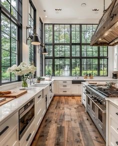 a large kitchen with white cabinets and wood flooring is pictured in this image, there are many windows on the wall