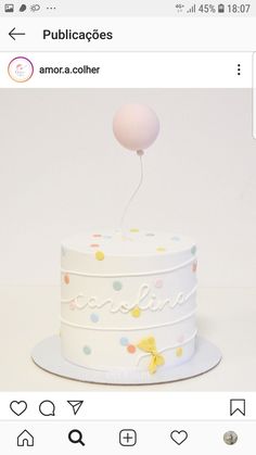 a white cake with polka dots on it and a balloon attached to the top layer