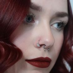 a woman with red hair and piercings on her nose