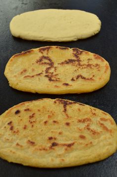 three flat breads sitting on top of a black counter next to each other with writing on them