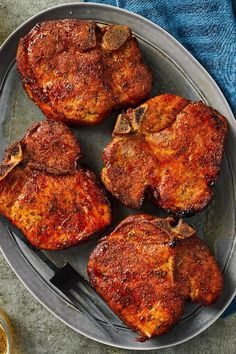 four pieces of meat sitting on top of a plate next to a knife and fork