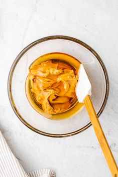 a bowl filled with food on top of a white counter next to a wooden spoon