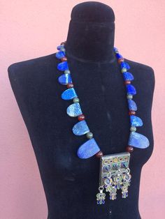 REDUCED from $650Striking necklace composed of  large one-side-rounded, one-side-straight, slabs of gorgeous raw matte Lapis Lazuli in graduated sizes (largest to the front), separated by green Labradorite & Carnelian ball-shaped-beads, framing a fabulous Moroccan Berber enamel & tribal-silver-metal prayer-amulet/talisman pendant box with 6 freely dangling parts, also in matching tribal-silver-metal & enamel, that may be  abstracted Hamsa symbols or flowers(?).  Smaller Labradorite b Artisan Jewelry With Natural Stones For Ceremonial Use, Artisan Jewelry With Natural Stones For Ceremonial Occasions, Artisan Jewelry With Natural Stones For Ceremonies, Artisan Necklace For Ceremonial Occasions, Bohemian Pendant Necklaces With Inlay, Bohemian Pendant Necklace With Inlay, Traditional Handmade Necklace With Rectangular Pendant, Handmade Traditional Necklace With Rectangular Pendant, Unique Natural Stone Necklaces For Festivals