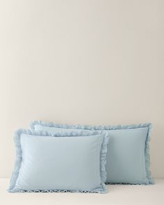 two blue pillows with ruffles on them