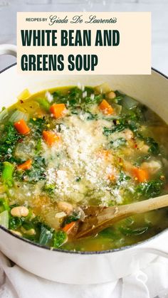 a white bean and greens soup in a pot with a wooden spoon on the side