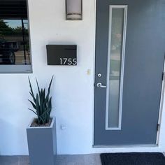 a door with a number plate on it next to two planters