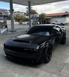 a black sports car parked at a gas station