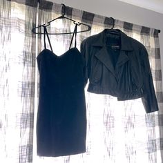 two black dresses hanging on a clothes rack in front of a window with sheer curtains