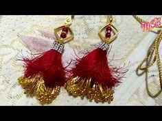 two pairs of red and gold earrings on top of a white table with a chain