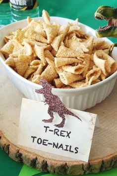 a bowl filled with cheetos sitting on top of a wooden tray next to a sign