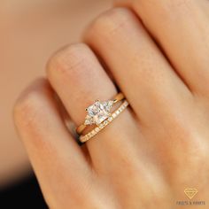 a woman's hand with a gold ring and two diamond engagement rings on it