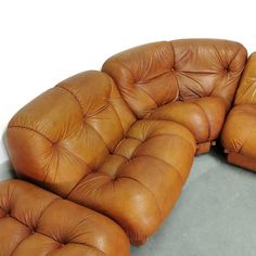 two brown leather couches sitting next to each other on top of a gray floor