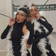 two women dressed in costumes taking a selfie with their cell phones while brushing their teeth