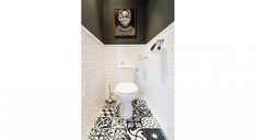 a white toilet sitting in a bathroom next to a black and white tile flooring