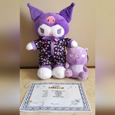 two stuffed animals sitting next to each other on a table with a certificate in front of them