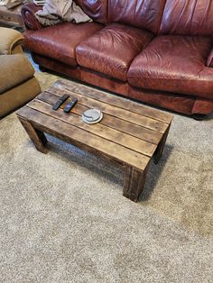 a wooden table sitting on top of a carpeted floor next to a brown couch