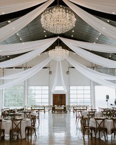 the inside of a wedding reception hall with chandeliers and white draping