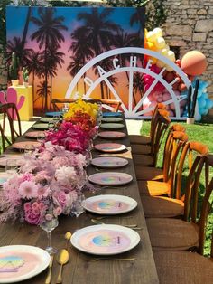 a long table set up for a party with plates and flowers on it, in front of a painting