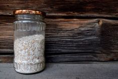 a glass jar filled with white rice sitting on top of a wooden table next to a wall