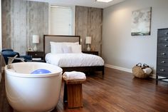 a large white bath tub sitting on top of a wooden floor next to a bed