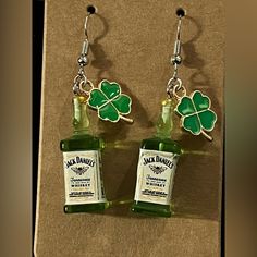 two bottles of jack daniels whiskey are hanging from earwires with clover leaves on them