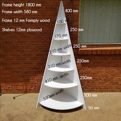 a tall white shelf sitting on top of a sidewalk next to a brick building with measurements