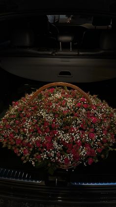 a basket filled with flowers sitting in the trunk of a car