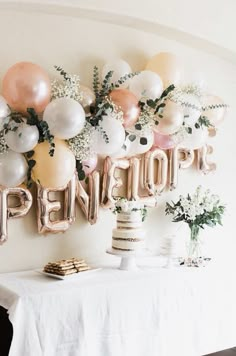 a table topped with balloons and cake next to a wall