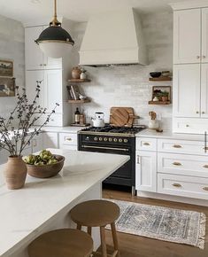 a kitchen with white cabinets and wooden stools in front of the stove top oven