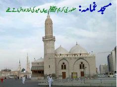 two men walking in front of a large building with arabic writing on the side of it