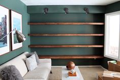 a living room with green walls and shelves on the wall, two white couches in front of a coffee table