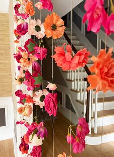 colorful paper flowers hanging from the ceiling in front of a stairway way with stairs and railings