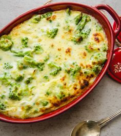 a casserole dish with broccoli and cheese in it next to a spoon