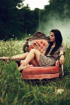 a woman sitting on top of a chair in the grass