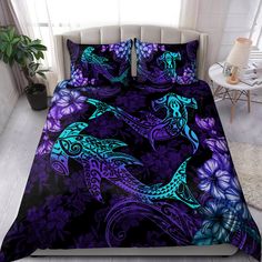 a bed covered in purple and blue comforters with two dolphins on the ocean side