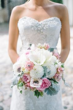 a bride holding a bouquet of white and pink flowers