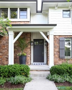 the front entrance to a house with plants and bushes