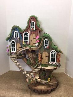 a tree stump with a house on top of it and flowers growing out of the windows