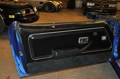 the interior of a car in a garage with other cars behind it and one door open