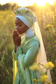 a woman in a green dress and white headdress standing in a field with flowers