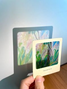 a person holding up a card with an image of a tree and flowers on it