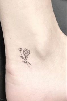 a small flower tattoo on the side of a woman's foot, which is also in black and white