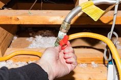 a person holding a yellow hose in their hand and some wires attached to the wall