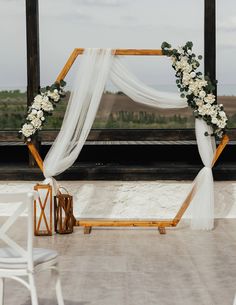 a wedding arch decorated with white flowers and greenery on the roof of a building