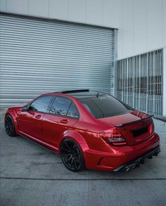 a red car parked in front of a garage door with roller doors on the side