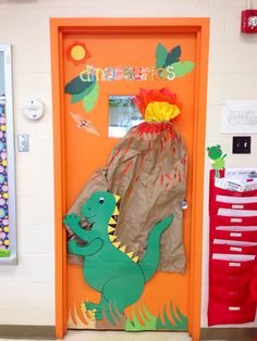 an orange door decorated with paper bags and a green dinosaur on it's back