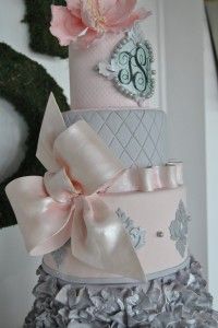 a three tiered cake with pink and gray decorations